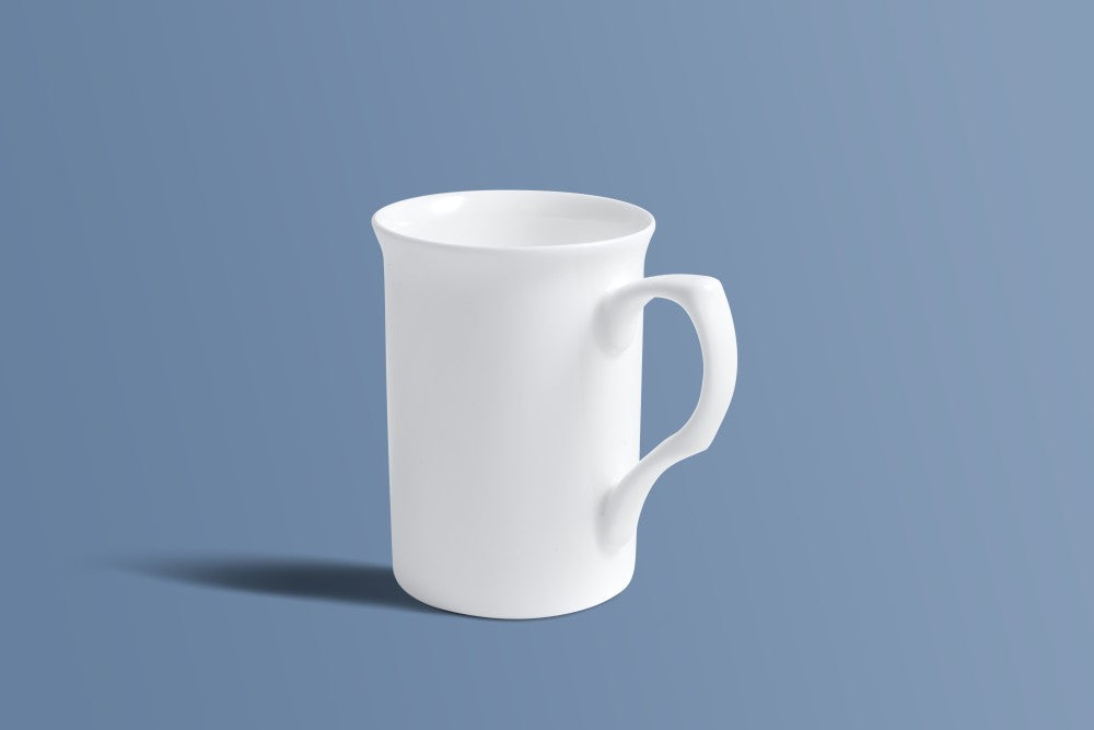 Plain white bone china mug at an angle, showing the shaped handle and tall silhouette.