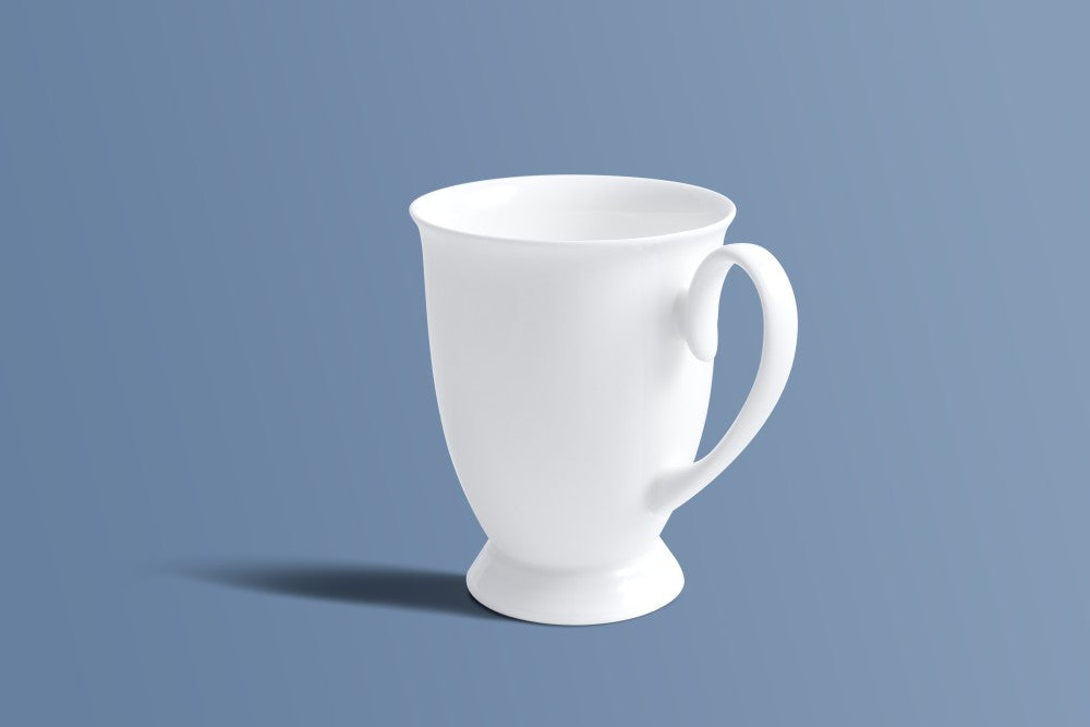 Plain white bone china footed mug at an angle, showing the shaped handle.