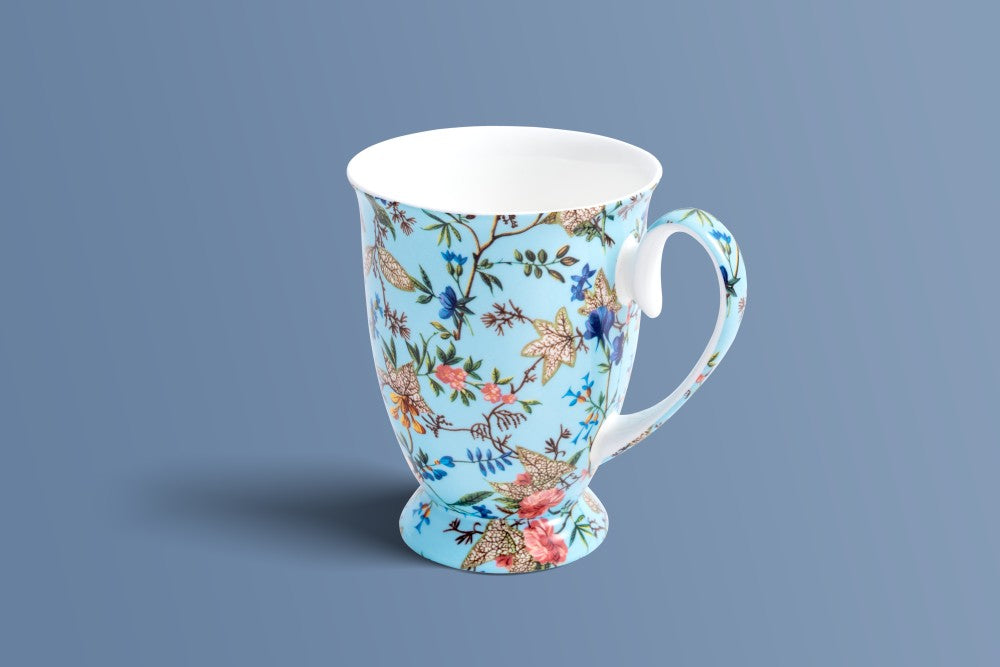 Botanica Blue bone china mug showing the pedestal foot and blue, blush and gold floral pattern.