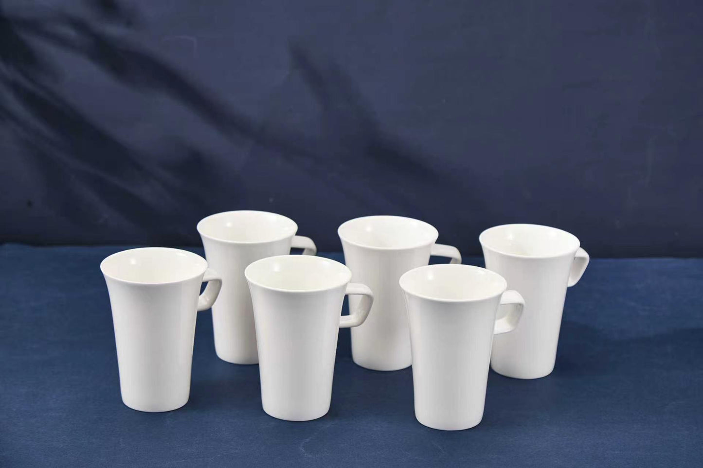 Set of white ceramic mugs on a blue background
