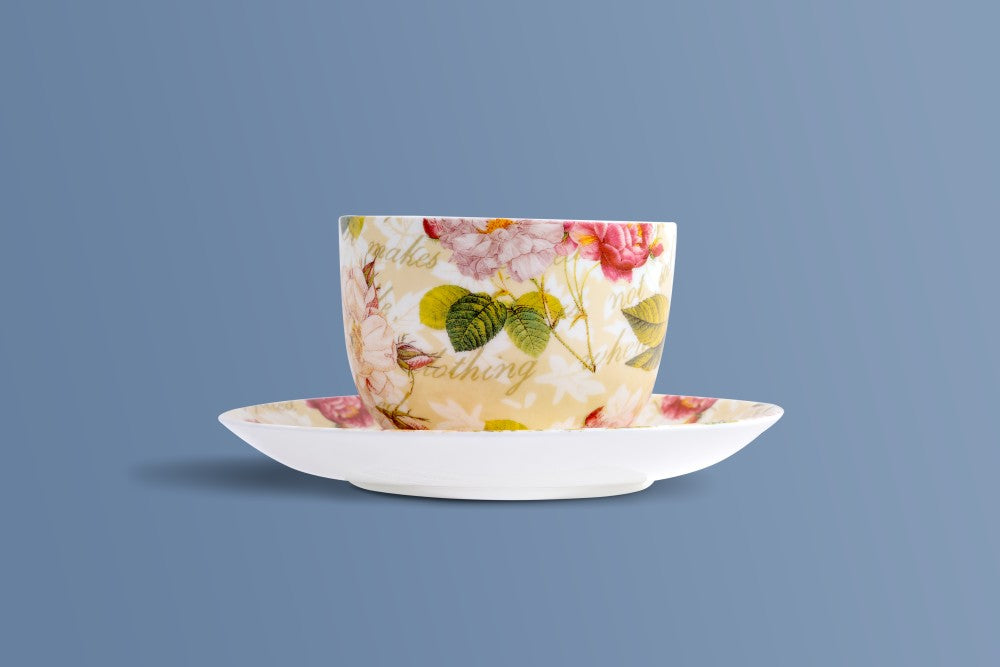 Rose & Verse bone china coffee cup showing the roses and handwritten script, with a white saucer.